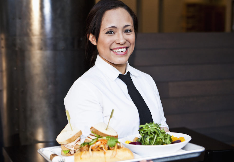 Server holding a salad and sandwich