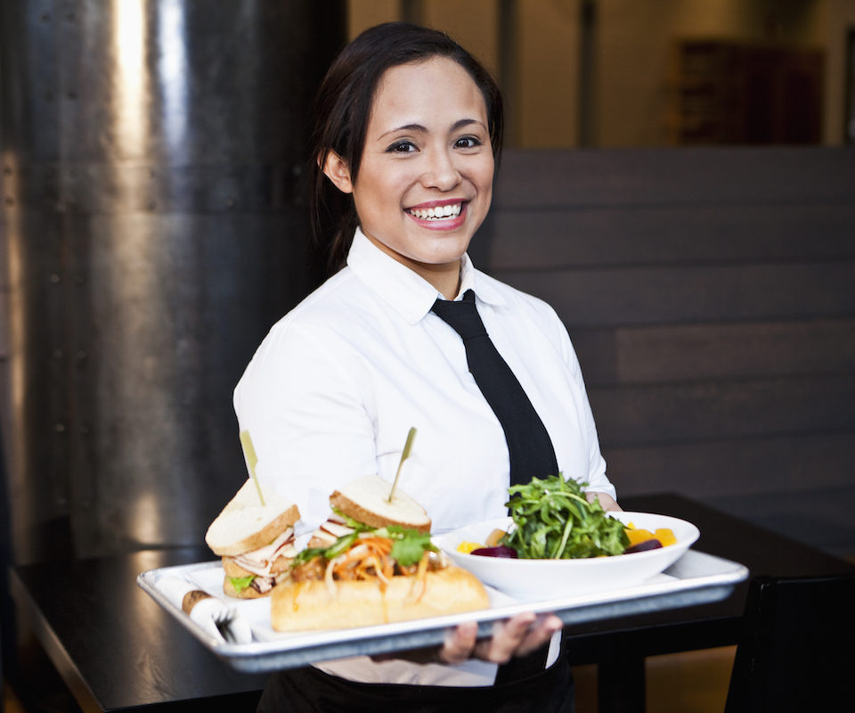 Server holding a salad and sandwich