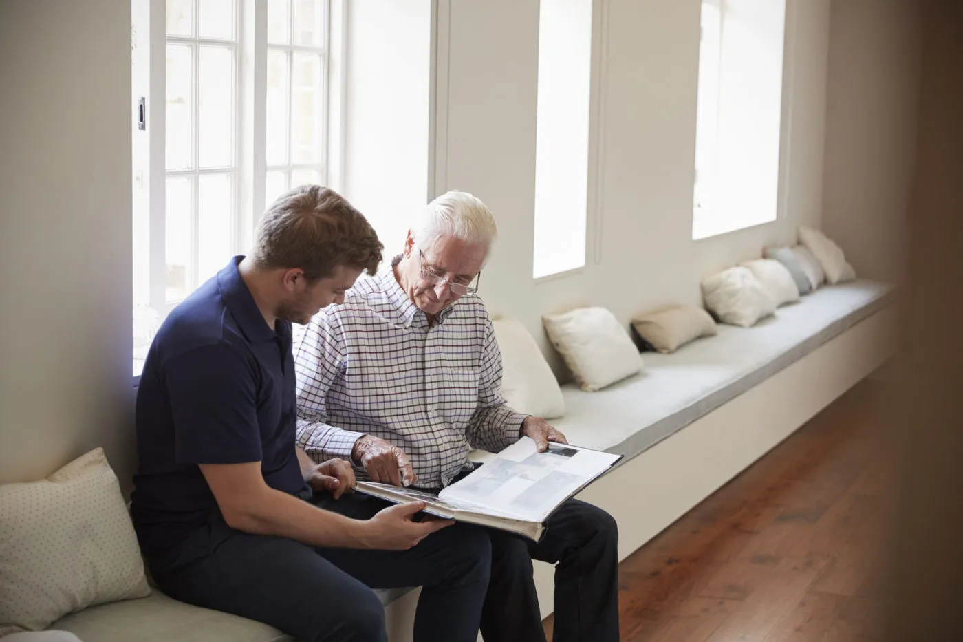 Caregiver and senior man looking at a photo album together.