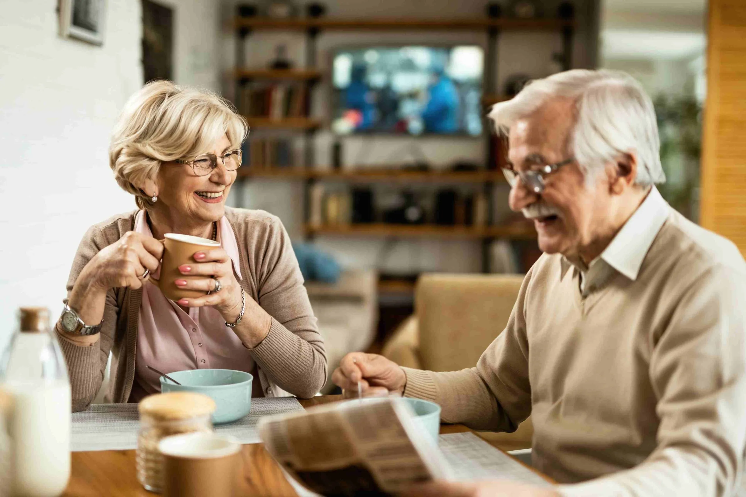 A man and woman enjoying cups of coffee and cereal.