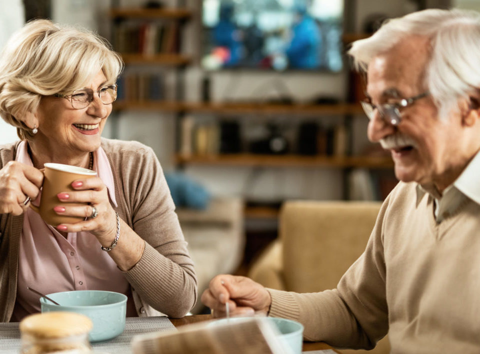 A man and woman enjoying cups of coffee and cereal.