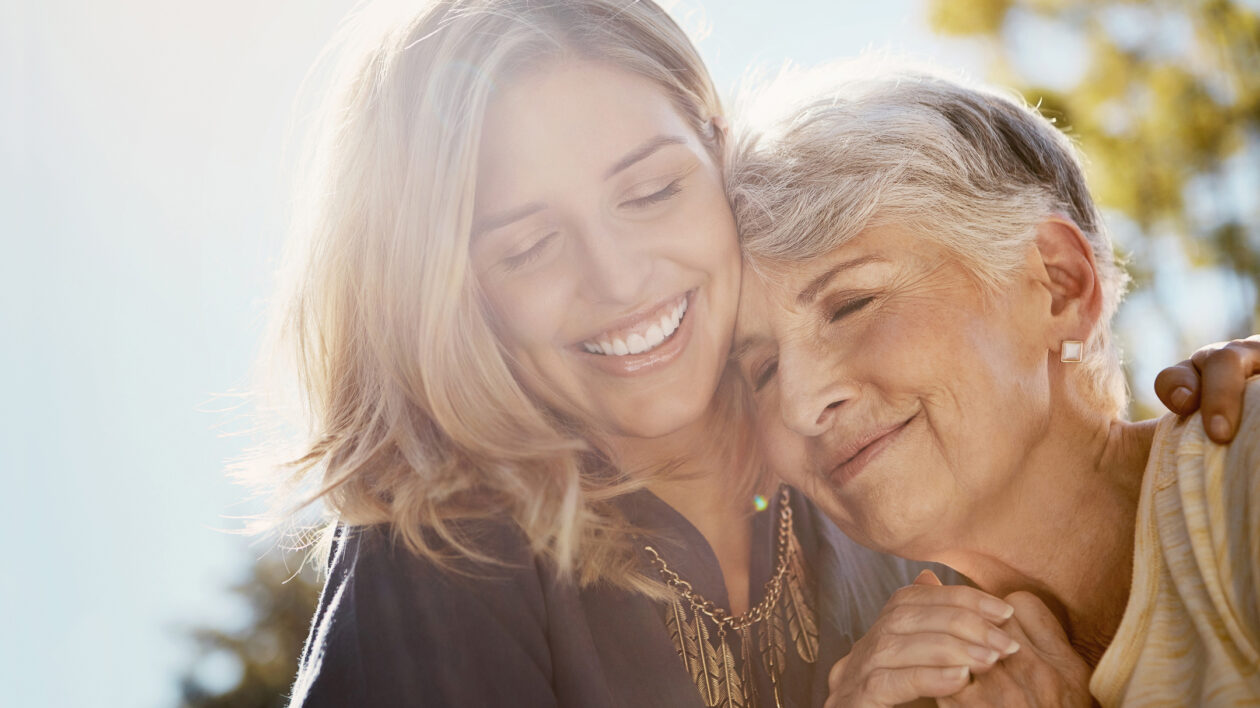 A photo of an older woman and her daughter hugging closely.