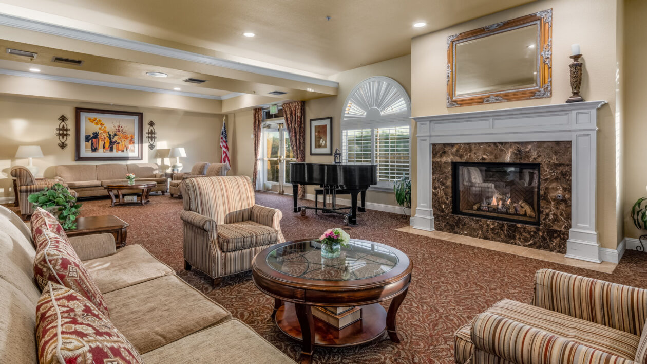 A luxurious seating area surrounds a decorative fireplace with a piano in the background.