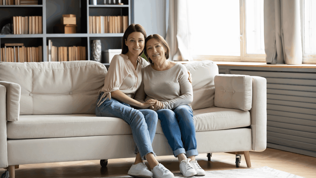 daughter holding her mother on a couch in living room