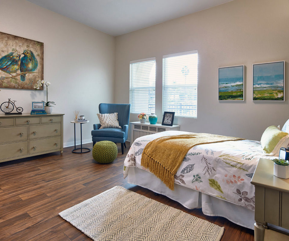 Comfortable bed and a chair and bright windows in the Sienna Bedroom