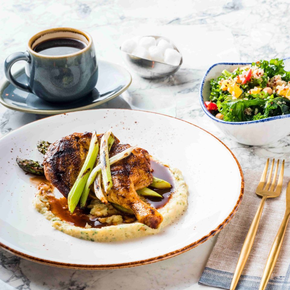 Chicken plated and presented with salad and coffee.