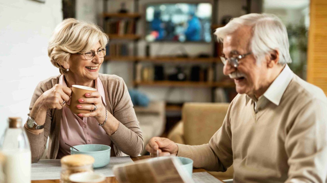 A man and woman enjoying cups of coffee and cereal.