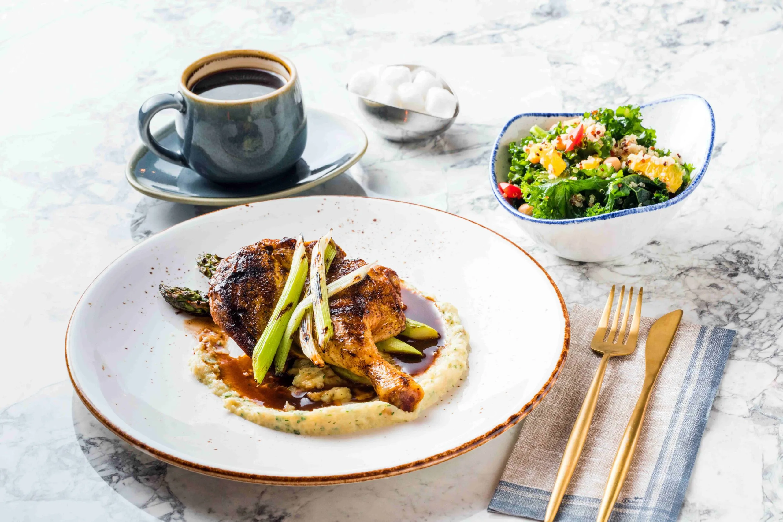 Chicken plated and presented with salad and coffee.