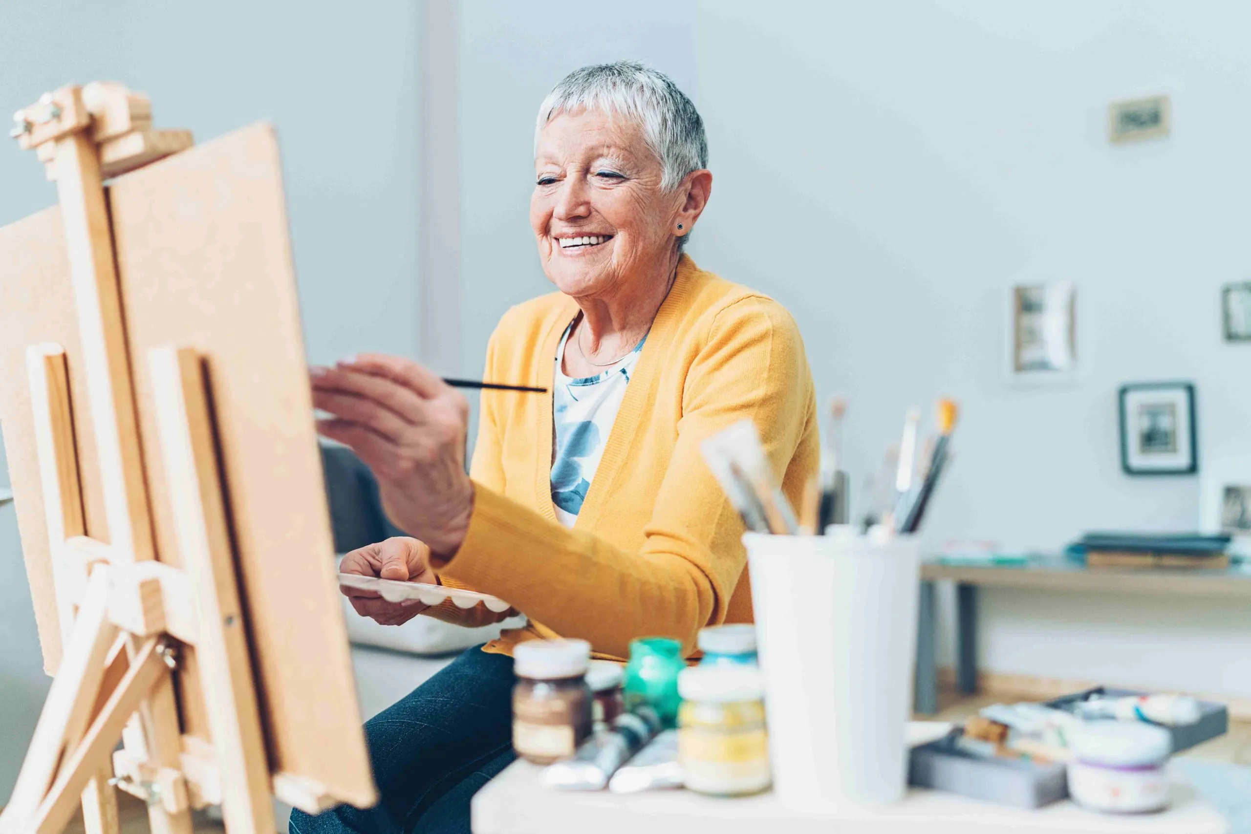 Woman smiling as she paints on a canvas.