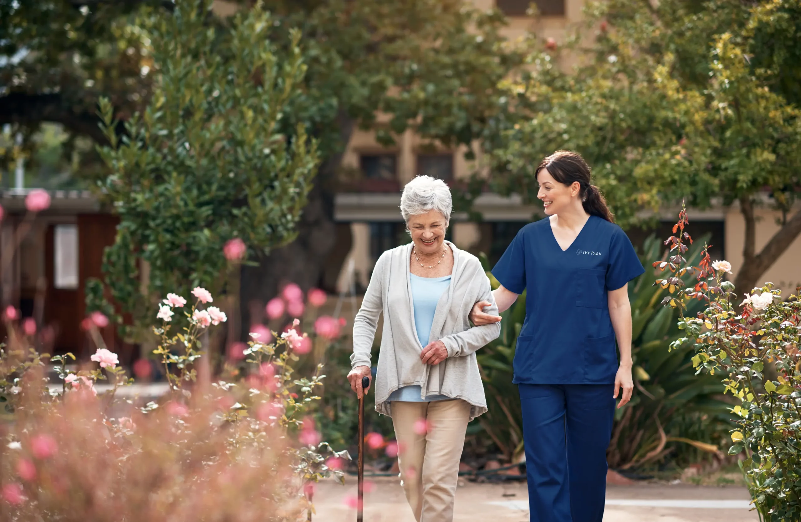 Senior walking with staff, trees and flowers in the background.