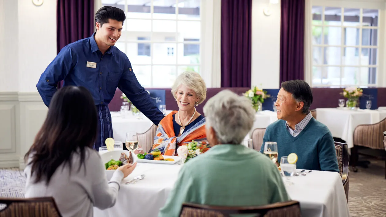 caregiver-talking-to-4-sitted-senior-people-dining
