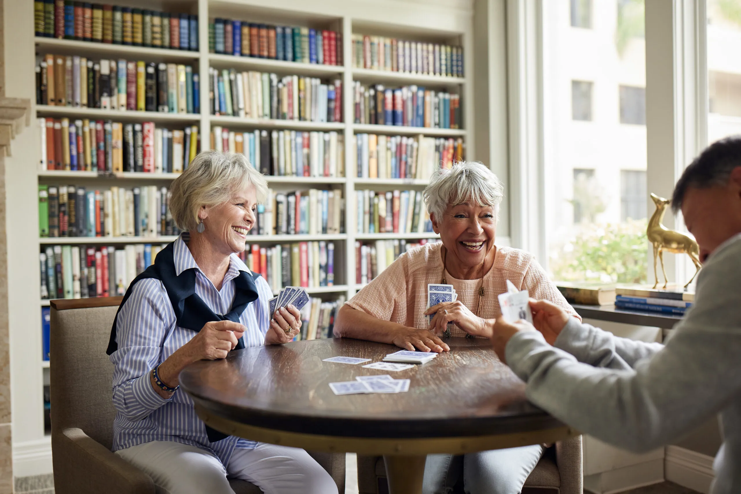 3-seniors-playing-cards-with-books-in-the-background