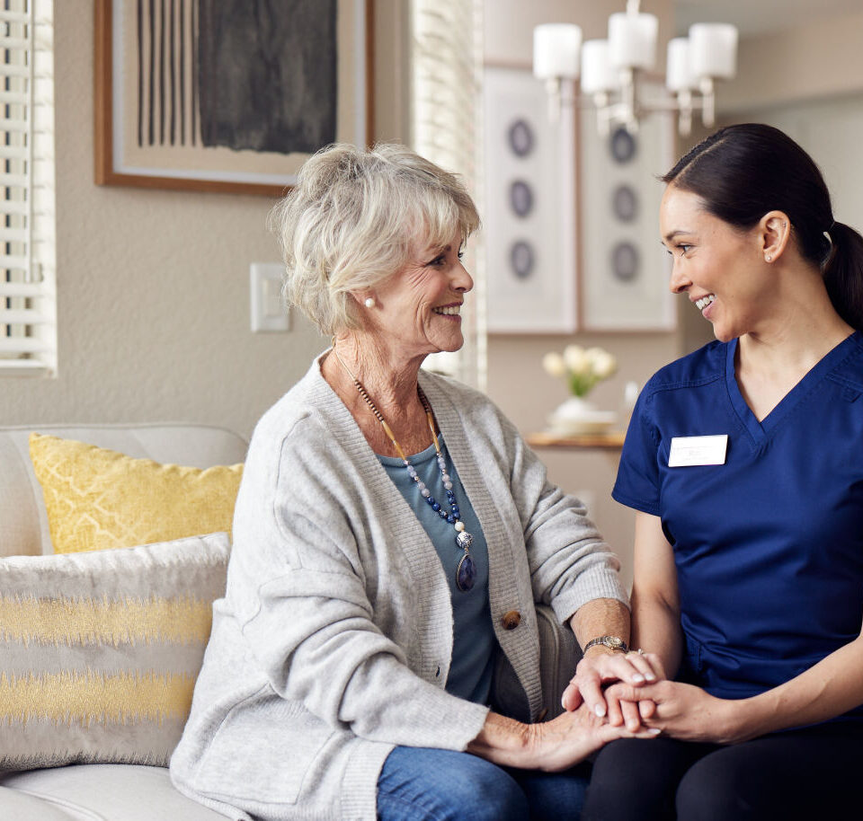 Happy senior woman holding nurse’s hand in a care home